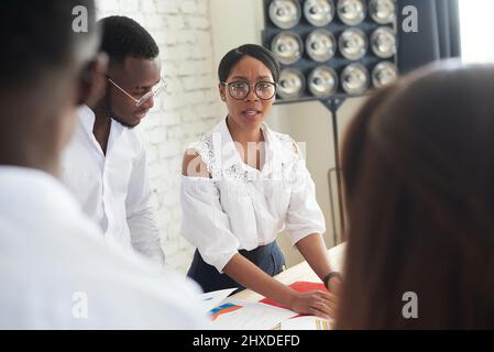 Réunion multiraciale entre le pdg afro-américain et l'équipe d'entreprise, avec des hommes d'affaires variés, discussion entre le dirigeant et la femme noire du projet pla Banque D'Images