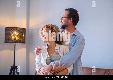 Couple d'adultes heureux profiter de la maison de noew après prêt et hypothèque. Concept d'acheteurs de propriété de maison. Homme et femme embrassant et souriant à l'intérieur de l'appartement appréciant Banque D'Images