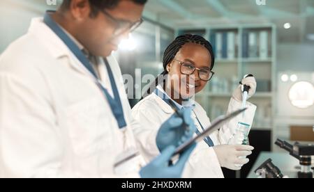 Découvrir quelque chose de nouveau. Portrait d'un jeune scientifique travaillant aux côtés d'un collègue dans un laboratoire. Banque D'Images