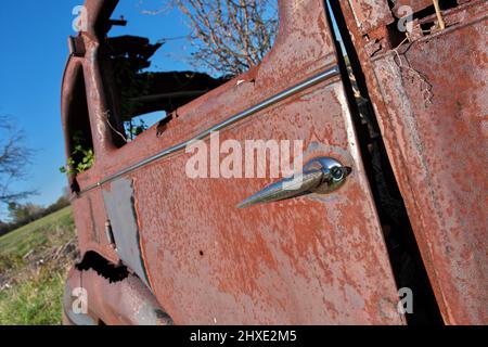 Gros plan sur la porte d'une ancienne voiture ancienne abandonnée et rouillée dans un champ de ferme lors d'une journée ensoleillée Banque D'Images