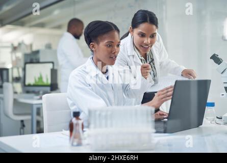 Améliorer les vies une collaboration à la fois. Photo de deux jeunes scientifiques utilisant un ordinateur portable dans un laboratoire. Banque D'Images