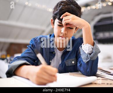 Axé sur sa scolarité. Image d'un jeune garçon qui fait ses devoirs. Banque D'Images