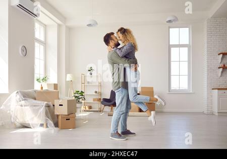 Couple heureux câlin célébrer la réinstallation à la maison Banque D'Images