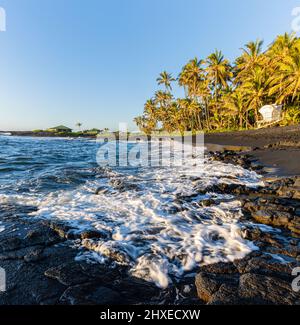 Lever du soleil sur les vagues s'écrasant contre le littoral de Pahoehoe Lava de Punalu'u Beach, Hawaii Island, Hawaii, États-Unis Banque D'Images