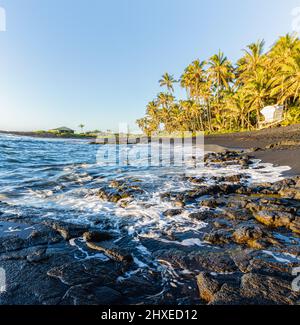 Lever du soleil sur les vagues s'écrasant contre le littoral de Pahoehoe Lava de Punalu'u Beach, Hawaii Island, Hawaii, États-Unis Banque D'Images