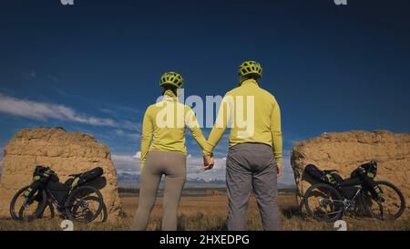 L'homme et la femme voyagent à vélo sur terrain mixte avec bikepacking. Les deux personnes voyage avec des sacs de vélo. Sport vêtements de sport dans le vert bla Banque D'Images