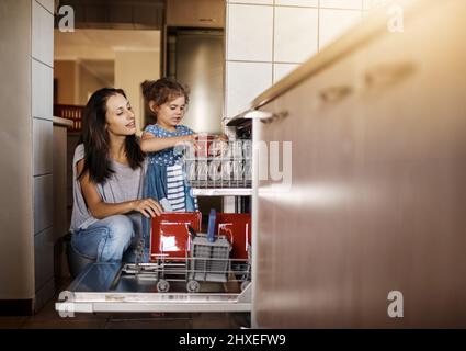 C'est ainsi que nous empilons le lave-vaisselle. Photo d'une petite fille mignonne et de sa mère en train de charger le lave-vaisselle ensemble à la maison. Banque D'Images