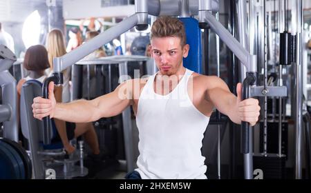 jeune homme européen bien formé utilisant les machines de gym de plate-forme pec à l'intérieur Banque D'Images