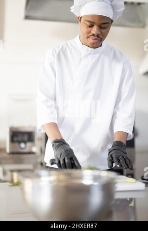 Portrait d'un jeune chef latino-américain cuisiné en uniforme dans la cuisine professionnelle. Un homme charmant qui travaille comme cuisinier au restaurant Banque D'Images