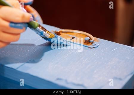 Gros plan des mains peintes avec une grande peinture à la brosse ancien tiroir de placard en bois de couleur bleue. Réutilisation des objets anciens. Des actions écologiques durables Banque D'Images