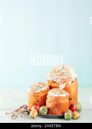 Gâteau de Pâques ukrainien traditionnel russe Kulich. Pain de Pâques chrétien orthodoxe ou gâteau de Pâques avec glaçage, œufs de Pâques et brindilles de saule sur fond bleu. Copier l'espace pour le texte, vertical Banque D'Images