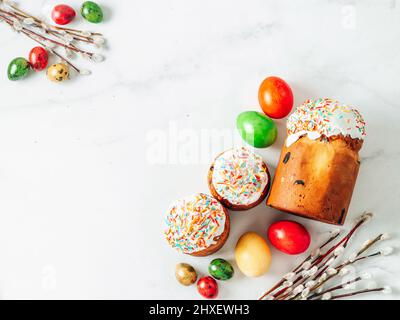 Gâteau de Pâques ukrainien traditionnel russe Kulich. Pain de Pâques chrétien orthodoxe ou gâteau de Pâques avec glaçage, œufs de Pâques et brindilles de saule sur fond de marbre blanc. Copier l'espace. Mise à plat ou vue de dessus Banque D'Images