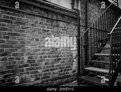 Une ancienne allée de briques avec escalier en fer noir et blanc Banque D'Images