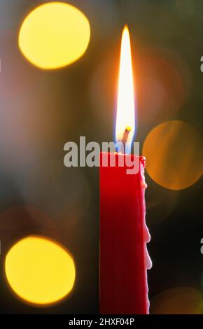 Gros plan d'une bougie rouge avec des lumières de noël en arrière-plan. Mise au point sélective et faible profondeur de champ. Banque D'Images