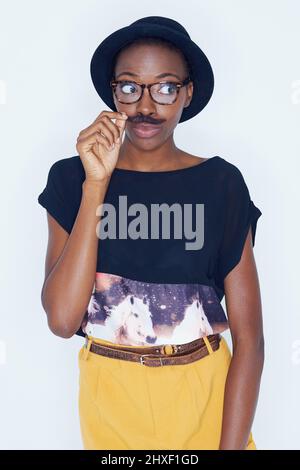 Exprimant son côté enfant. Une jeune femme posant contre le blanc. Banque D'Images