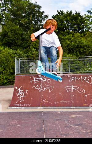 Jeune garçon avec un scooter va airborne Banque D'Images