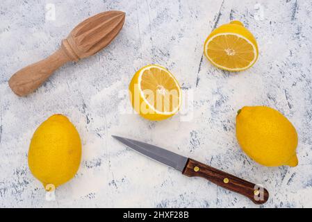 Citron frais coupé en deux avec un couteau de cuisine et une centrifugeuse sur fond blanc-gris. Vue de dessus. Banque D'Images