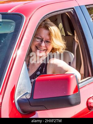 Smiling woman conduit une voiture rouge Banque D'Images