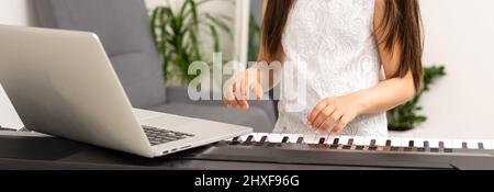 une petite fille apprend à jouer le synthétiseur. apprendre à jouer des instruments de musique. Banque D'Images