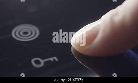 Personne utilisant les commandes tactiles d'une table de cuisson moderne à dessus de verre pour allumer une plaque électrique. Action. Gros plan sur la mise en marche de la table de cuisson à induction. Banque D'Images