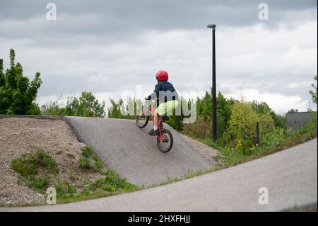 Enfant à bord de son vélo bmx sur une piste de pompe lors d'une journée nuageux. Banque D'Images