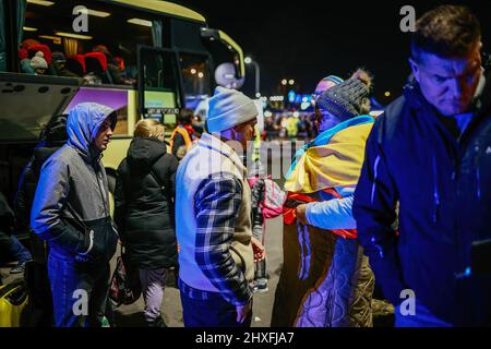 Un réfugié portant un drapeau ukrainien vu devant un bus. Ancien centre commercial de Przemysl, transformé par des bénévoles en l'un des plus grands centres d'aide aux réfugiés de la région. Depuis le début de l'invasion russe de l'Ukraine, plus de 1,4 millions de personnes ont fui en Pologne pour échapper à la guerre. Les réfugiés ukrainiens sont accueillis avec un soutien complexe de la part des organisations caritatives et des Polonais ordinaires, mais de nombreux experts humanitaires indiquent qu'avec un tel afflux de personnes et un soutien insuffisant du gouvernement polonais, une crise pourrait se produire en quelques semaines. (Photo de Filip Radwanski Banque D'Images
