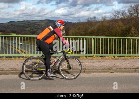 Cycliste mâle à cheval Boardman CXR 9,8, vélo tout terrain sur route de campagne traversant le pont d'autoroute dans la campagne du Lancashire, Royaume-Uni Banque D'Images