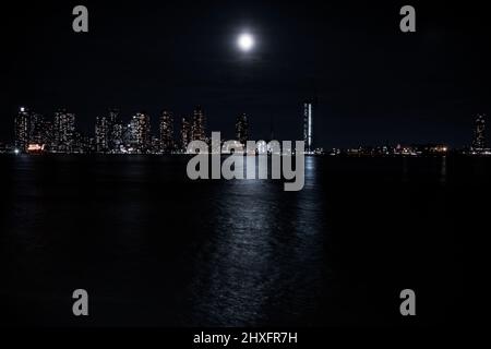 Une grande lune lumineuse brille au-dessus de l'East River depuis Queens Banque D'Images