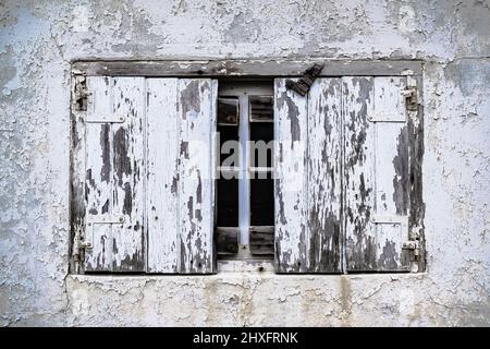 Une vieille fenêtre boarée cassée avec peinture blanche qui s'écaille. Banque D'Images