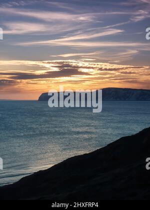 Un coucher de soleil radieux et glorieux sur la mer et les promontoires de la falaise de craie de l'île de Wight, avec les riches rayons dorés reflétés dans les eaux texturées. Banque D'Images