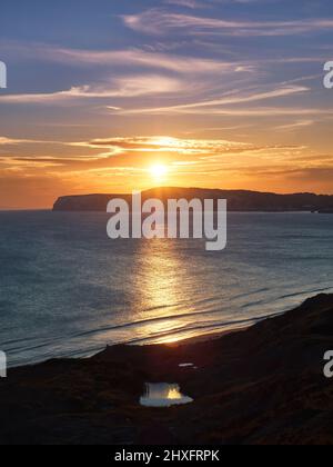 Un coucher de soleil radieux sur la mer et des promontoires de falaises de craie avec de riches rayons dorés reflétés dans les eaux texturées et une petite piscine reflétant le disque solaire. Banque D'Images