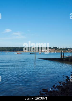 Pourtant, des eaux limpides et vivivivitreux dans un port de l'île de Wight, abritant des yachts éloignés dans un port entouré de collines sous un ciel bleu profond. Banque D'Images