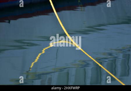 Bateau à voile nylon jaune double tresse corde d'amarrage sur la surface bleue de l'eau de mer. Banque D'Images