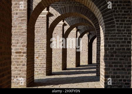 Vue en perspective décroissante entre le couloir entre le chemin de brique sous la structure de brique d'arc de l'ancien amphithéâtre romain. Banque D'Images