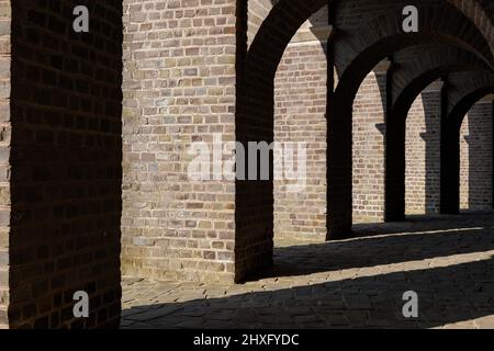 Vue en perspective décroissante entre le couloir entre le chemin de brique sous la structure de brique d'arc de l'ancien amphithéâtre romain. Banque D'Images