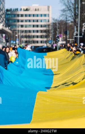 Immense drapeau ukrainien à Vilnius, porté par des personnes agitant des drapeaux lituaniens et ukrainiens lors d'une manifestation contre la guerre Banque D'Images