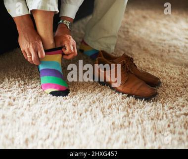 Ajoutez un peu de plaisir à la tenue. Photo courte d'un homme mettant des chaussettes et des mocassins colorés. Banque D'Images