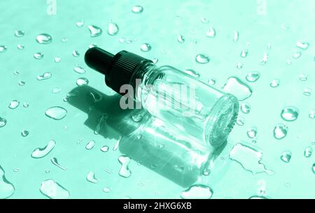 Sérum cosmétique pour le soin de la peau en flacon en verre sur fond vert avec gouttes d'eau. Vue de dessus Banque D'Images
