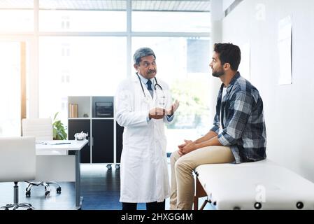Ce qui semble être la question, monsieur. Cliché d'un médecin et d'un patient hommes matures ayant une discussion au bureau des médecins avant un examen. Banque D'Images
