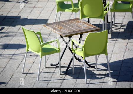 Chaises vertes en plastique et table en bois sur une terrasse ensoleillée. Saint-Gervais-les-bains. Haute-Savoie. Auvergne-Rhône-Alpes. Haute-Savoie. Banque D'Images