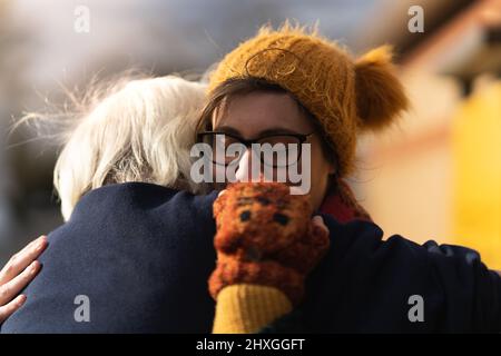 Les jeunes femmes embrassant son grand-père après une longue séparation, se rencontrant à l'extérieur des femmes portent un foulard laineux chapeau et des gants Banque D'Images