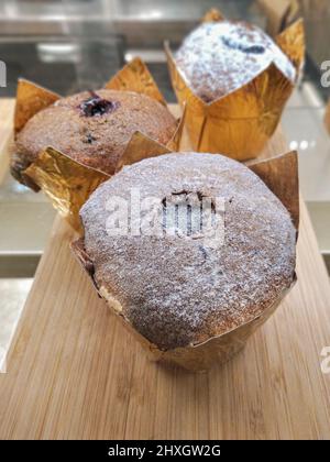 muffins au chocolat avec garniture au chocolat en papier doré sur une vitrine de café-boutique, concept cupcake Banque D'Images