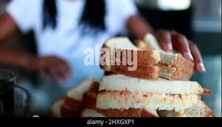 Les mains attrapant le sandwich. Prise manuelle de nourriture calorique Banque D'Images