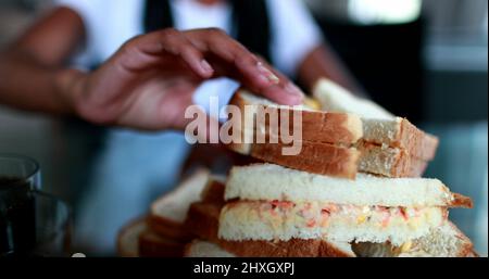 Les mains attrapant le sandwich. Prise manuelle de nourriture calorique Banque D'Images