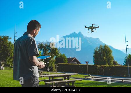 Jeune homme volant drone sur un paysage de montagne étonnant. Homme utilisant un drone avec télécommande pour prendre des photos et des vidéos aériennes. Banque D'Images