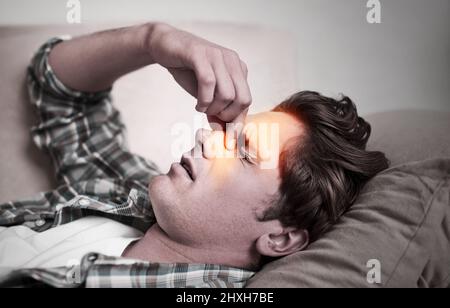 Mes sinus sont tellement bloqués. Un jeune homme qui tient la tête dans la douleur. Banque D'Images