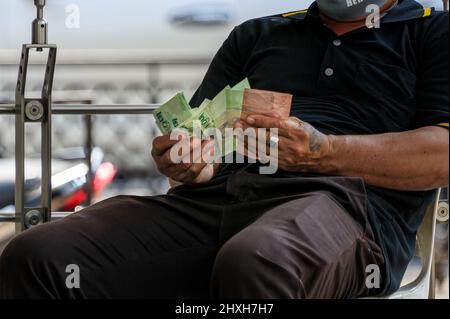 Un homme vérifie son argent. Il s'agit de billets de banque thaïlandais sous forme de cent baht et de vingt baht. Banque D'Images