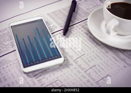 Photo d'un smartphone et d'une tasse de café au-dessus de la section affaires d'un journal. Tout le contenu de l'écran est conçu par nous et n'est pas protégé par des droits d'auteur Banque D'Images