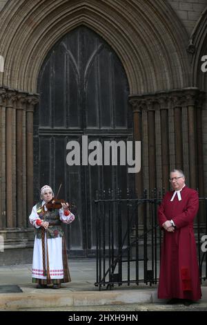 Un musicien au violon, vêtu d'une robe nationale lituanienne, joue des chansons lituaniennes et ukrainiennes regardées par le vice-doyen de la cathédrale de Peterborough Tim Alban Jones. À une époque où l'Ukraine est attaquée par la Russie de Vladimir Poutine, les Lituaniens célèbrent leur restauration le jour de l'indépendance à la cathédrale de Peterborough. Ils soutiennent l'Ukraine et tiennent les drapeaux et rubans ukrainiens. La Lituanie a retrouvé sa liberté de l'Union soviétique le 11th 1990 mars. Une courte prière et un silence d'une minute ont été organisés pour les défenseurs de la liberté déchus. (Photo de Martin Pope/SOPA Images/Sipa USA) Banque D'Images