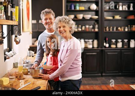 Journée de cuisson avec Nan et champs. Portrait d'une petite fille et de ses grands-parents qui cuisent ensemble dans la cuisine. Banque D'Images